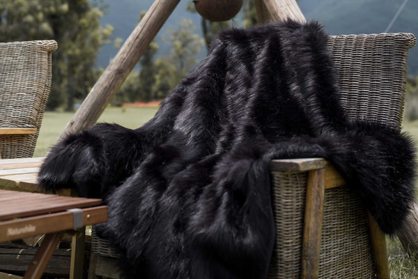 A queen size black faux fur throw blanket on the sofa. It is the softest fake fur blanket you can get. 