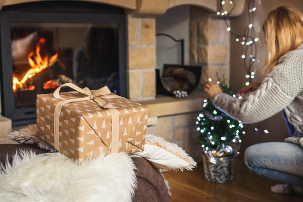 A white faux fur blanket and a Christmas gift in the living room, right in front of the fireplace.