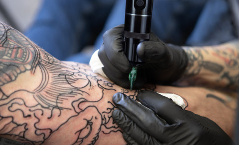 tattoo artist working with wireless tattoo machine