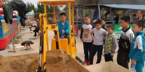 Los niños se reúnen en torno a una excavadora de juguete