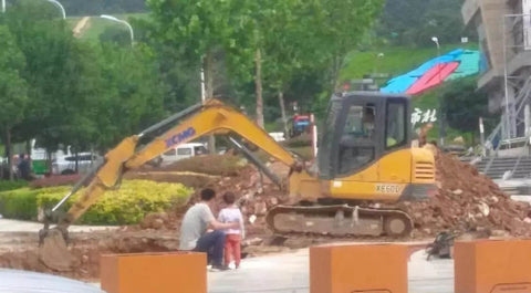 Un padre y su hijo mirando una excavadora en funcionamiento