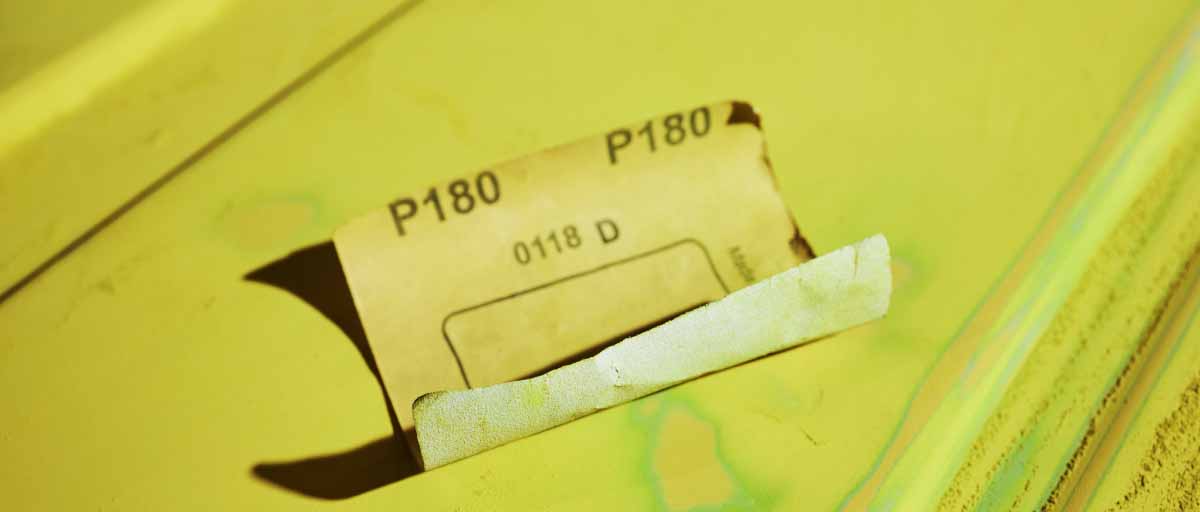 mit Schleifpapier der Körnung 180 den Rost vom Auto entfernen