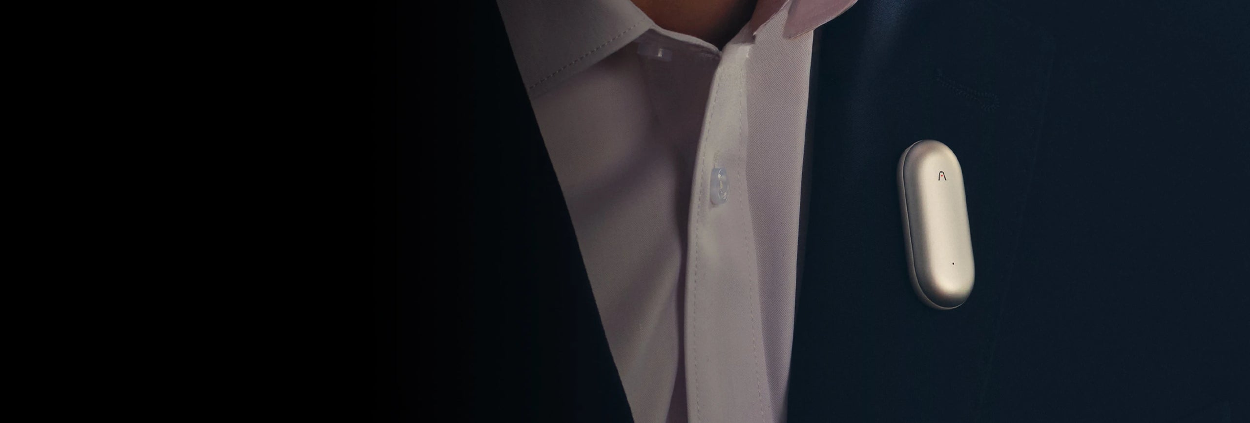 Silver Plaud NotePin clipped to a dark suit jacket lapel.