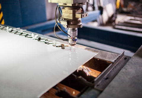 A laser engraver creating detailed graphics on multiple small plastic parts in a single run.