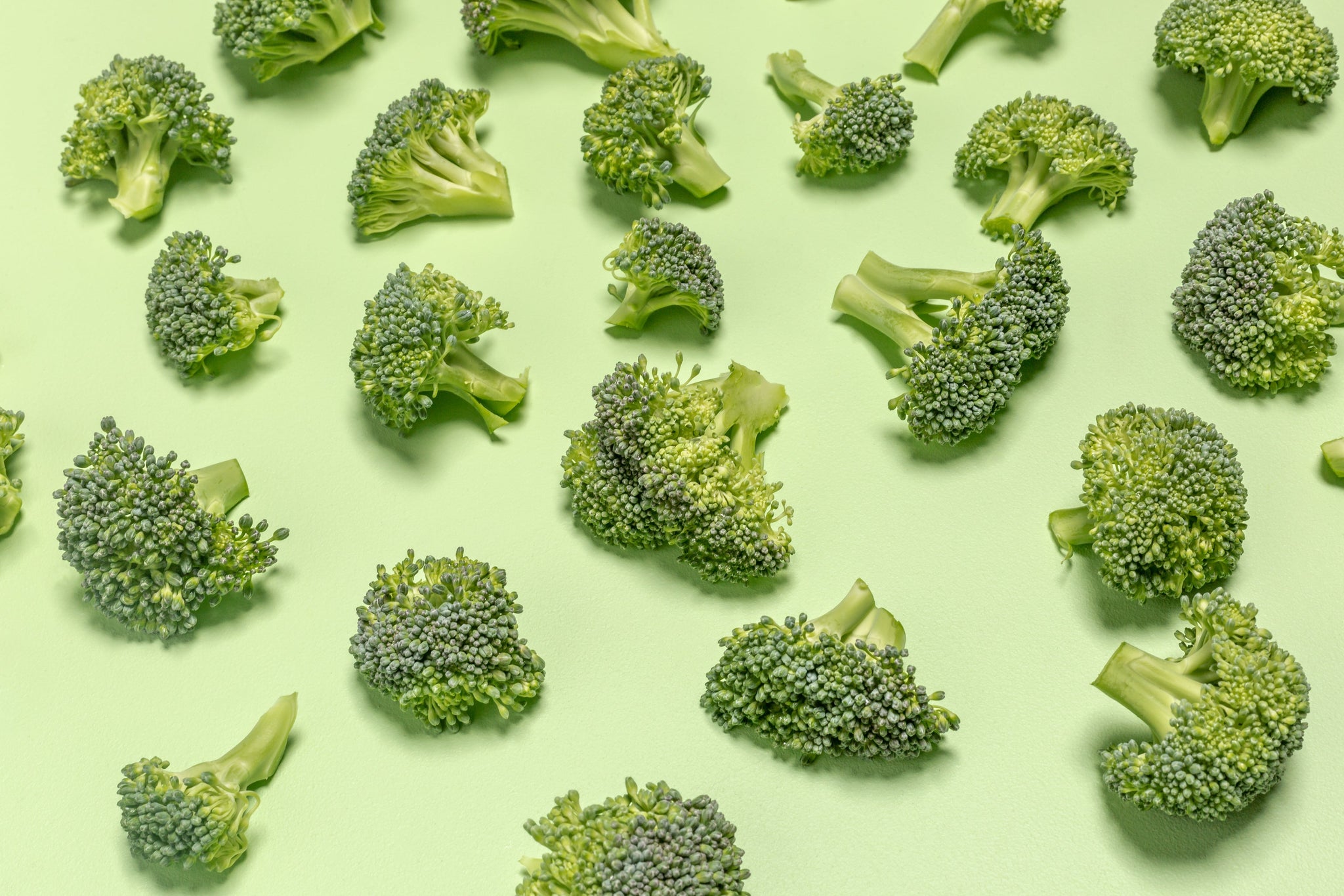 Broccoli Pieces On Green Surface Photo: Broccoli florets spaced out neatly on a pale-green surface. Look at all that green! Such fiber! Such healthy food choices!