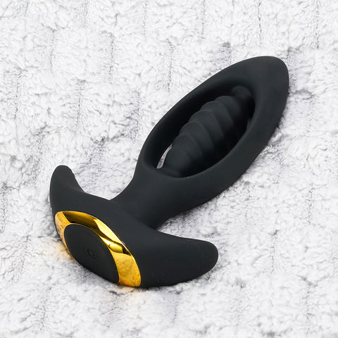 A black silicone anal plug with a gold accent and textured grip.