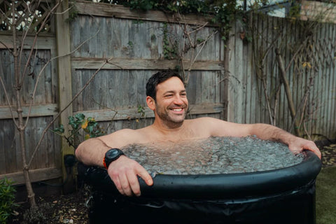 A man smiles while sitting in an ice bath, indicating the potential mood-enhancing benefits of the practice.