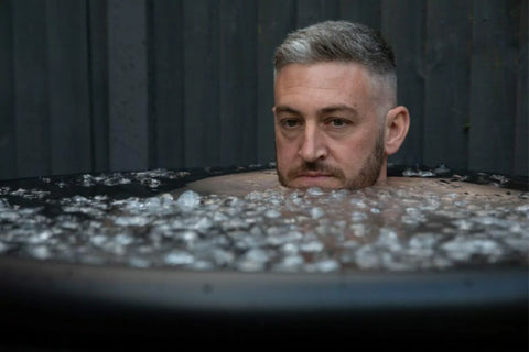 A man sits in an ice bath, focusing on mental and physical recovery.