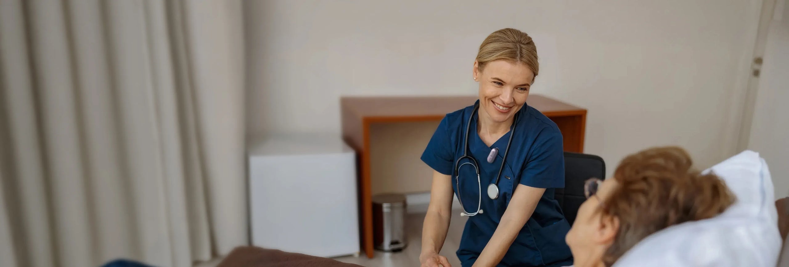 Nurse clipped with a purple Plaud NotePin S talks bedside with a patient, recording to stay focused and track their progress.