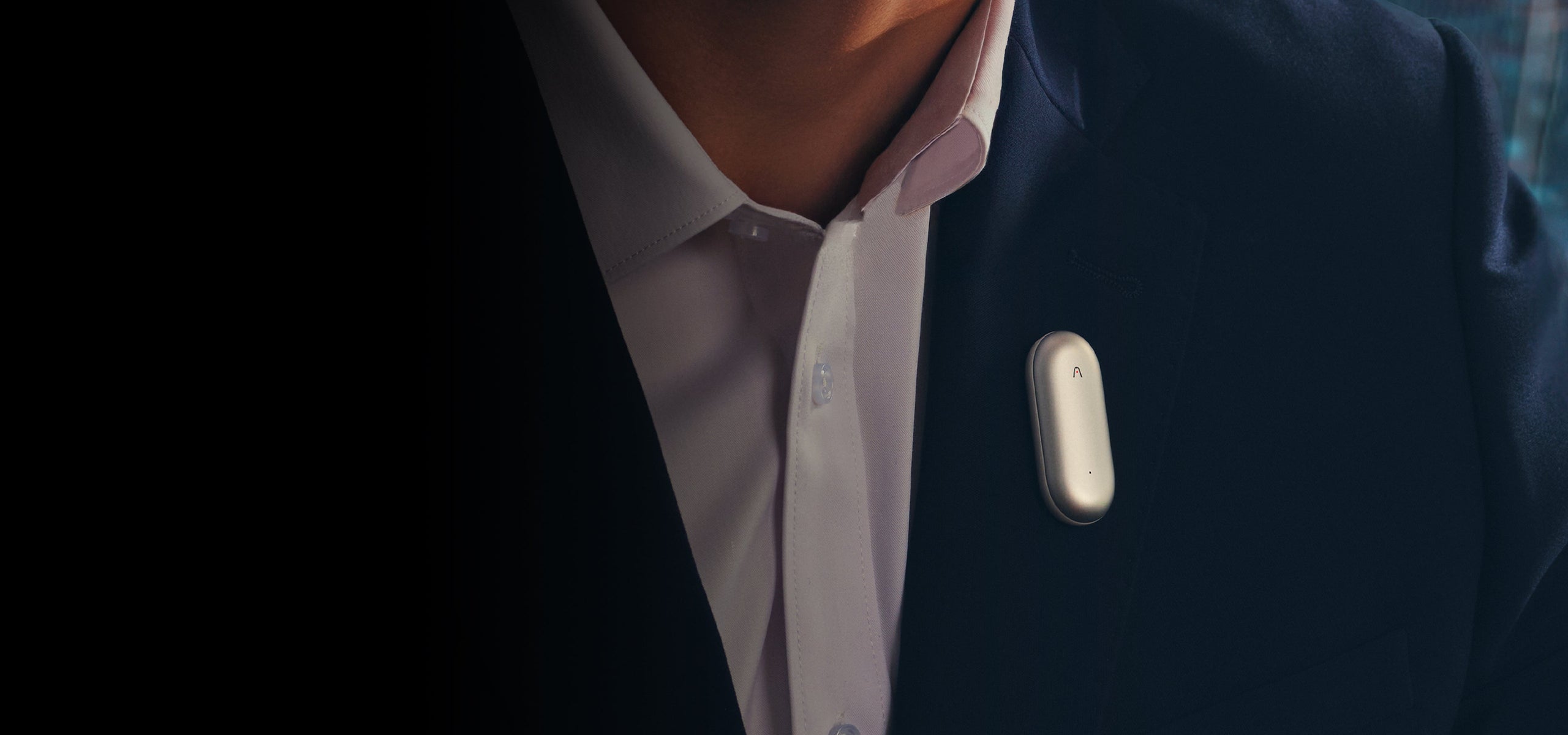 Silver Plaud NotePin clipped to a person's dark suit lapel.
