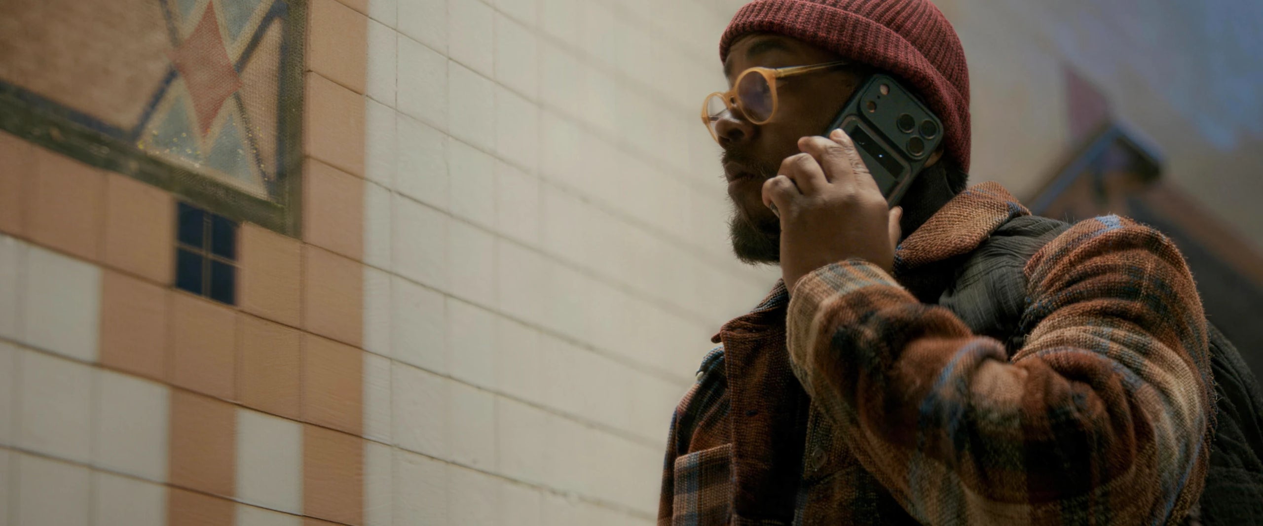 Man recording a phone call using a Plaud Note AI voice recorder attached to the back of his smartphone.