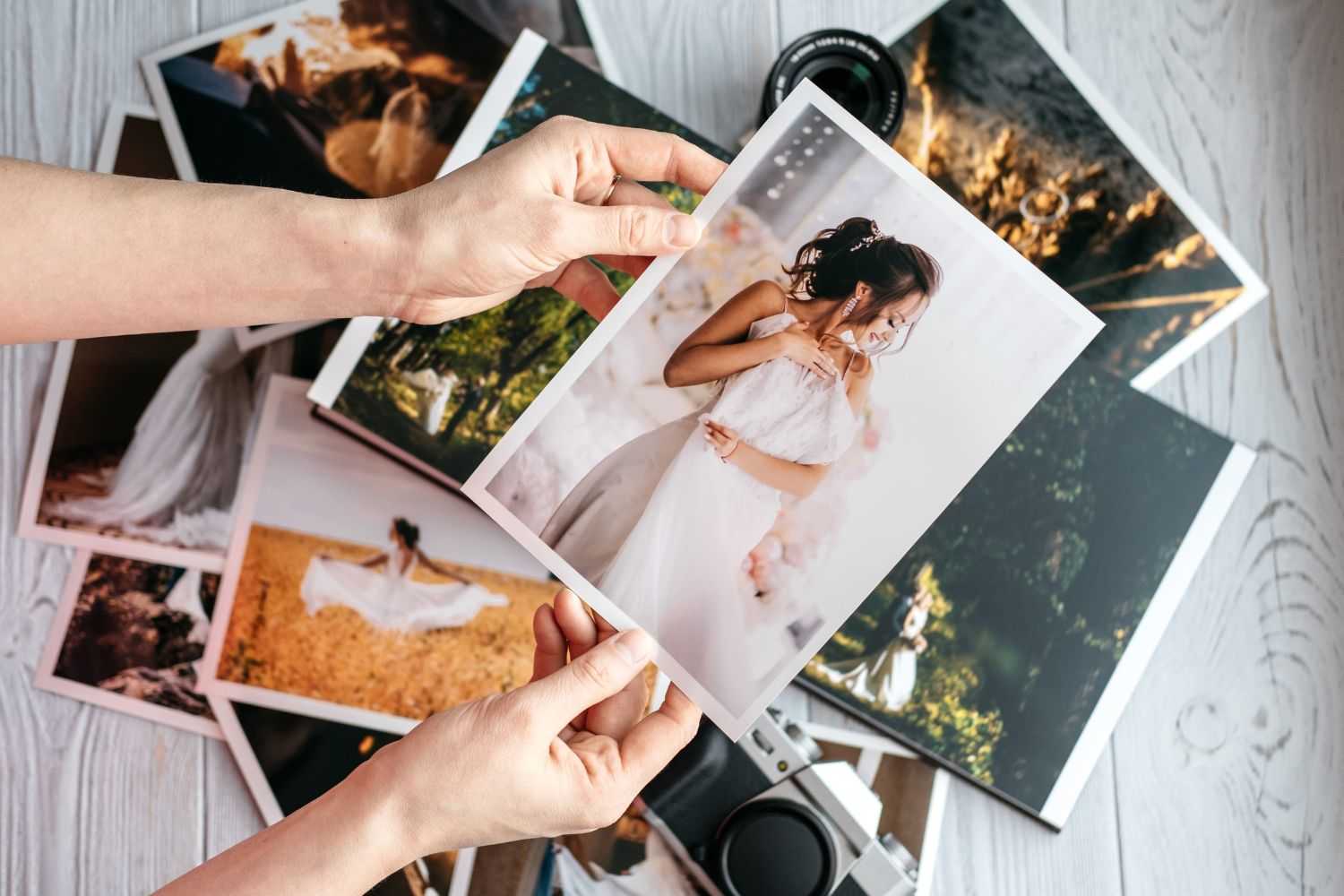 person holds one photo and others on the ground