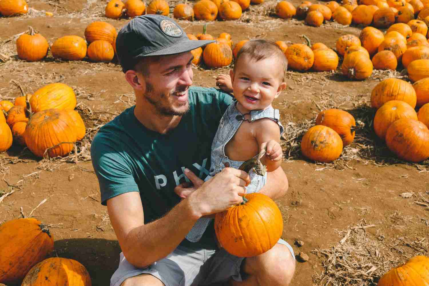 man is holding baby and pumpkin