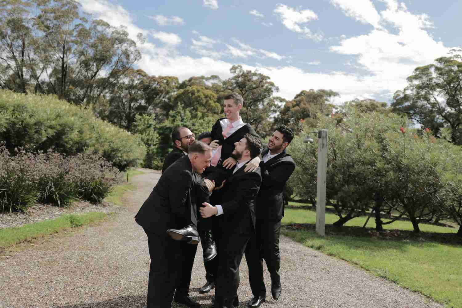 men are holding up the groom