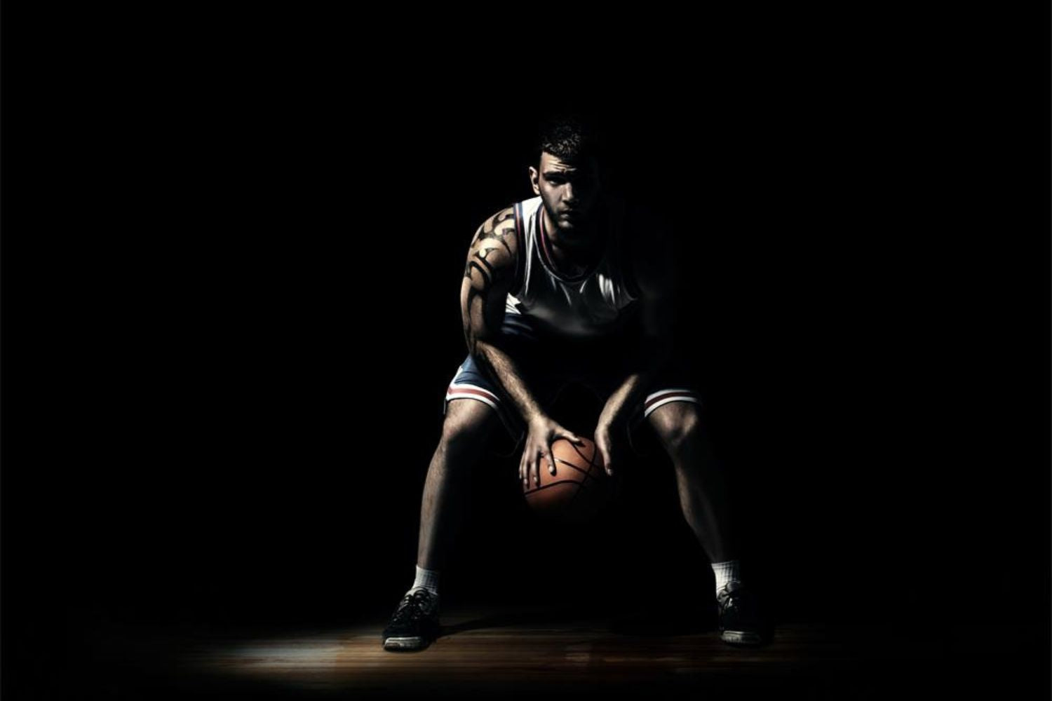 basketball player crouching and holding a basketball in hands